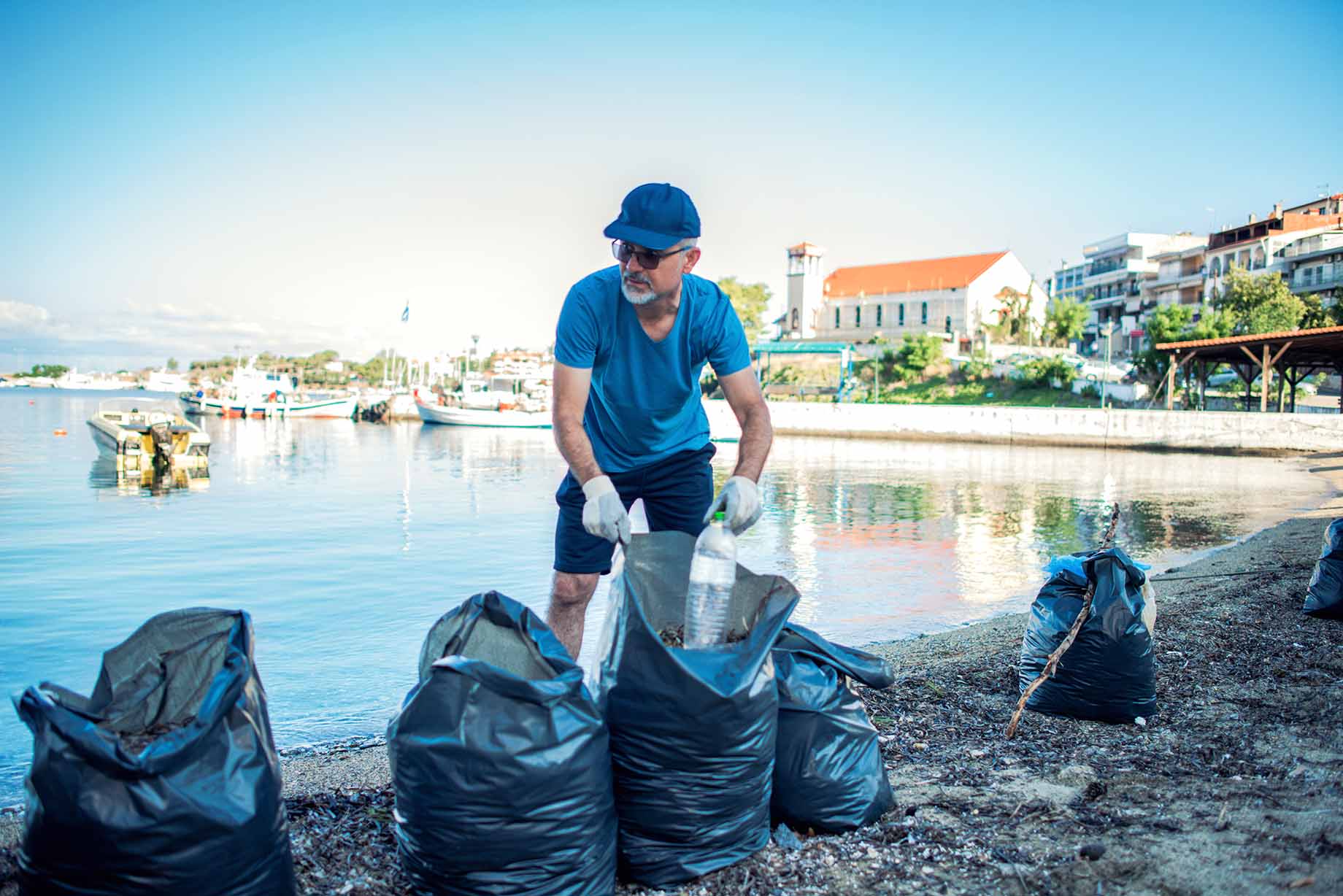 A man cleaning up trash on the beach